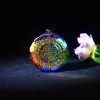 Chakra orgonite pendant with gold Sri Yantra on a dark background beside a flower