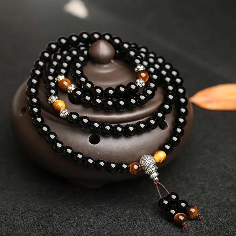 Black mala beads coiled around an incense burner