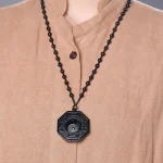 Obsidian bagua pendant worn against a tan top