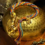 Colorful Tibetan braided bracelet on a brass bowl, side angle