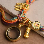 Close-up of the magnifying glass and prayer wheel charms on the braided bracelet