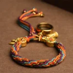 Colorful Tibetan braided bracelet coiled on a brown surface