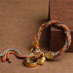 Colorful Tibetan braided bracelet with a prayer wheel charm and magnifying glass charm