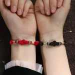 Two people wearing matching red and brown string bracelets together