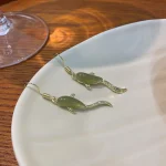 Dark green koi fish earrings on a white plate