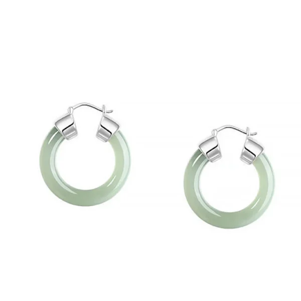 Pair of green jade hoop earrings with silver hinges on a white background