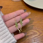 Green jade koi fish earrings held in a hand
