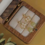 Gold drop earrings with shell flowers and jade beads in a case