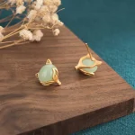Green jade and gold fox stud earrings at an angle