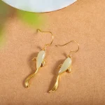 Gold koi fish earrings with green jade on beige