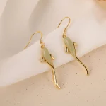 Gold koi fish earrings resting on white cloth