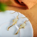 Gold koi fish earrings on a white plate