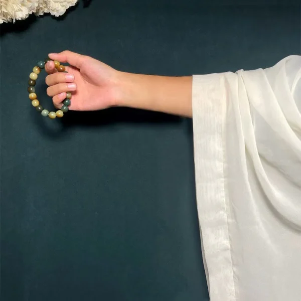Multicolor bodhi seed wrist mala held in a hand with a white sleeve