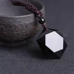 Black obsidian pendant lying beside a rough stone bowl