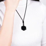 Woman in a white knit sweater wearing an obsidian pendant necklace
