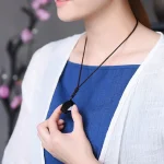 Woman wearing a black obsidian pendant necklace over a blue top