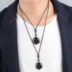 Man wearing two layered black obsidian pendant necklaces over a white top