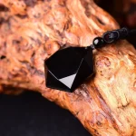Black obsidian pendant resting on a piece of grained wood