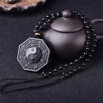 Black obsidian bagua pendant displayed with a teapot