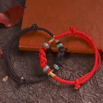Red and brown matching bracelets with jade beads resting on a red book
