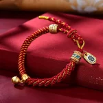 Red gold Tibetan braided bracelet with a round ghau prayer box