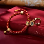 Red gold Tibetan braided bracelet with a ghau prayer box and bell