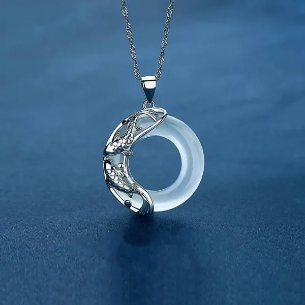 Sterling silver koi fish pendant necklace with a pale jade circle on a blue background