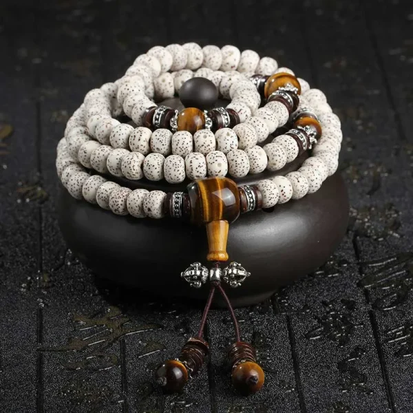 108 bodhi seed mala beads with tiger eye stones and silver accents coiled on a black stand