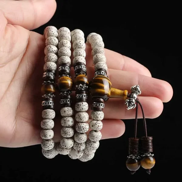 Bodhi seed mala with tiger eye stones held in a hand