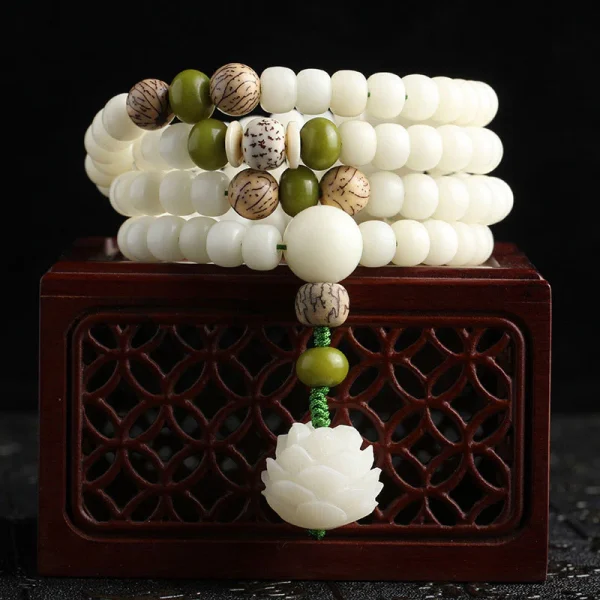 108 white bodhi seed mala beads with a lotus charm wrapped around a wooden box