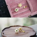 Back of white jade flower stud earrings with posts on a wooden tray